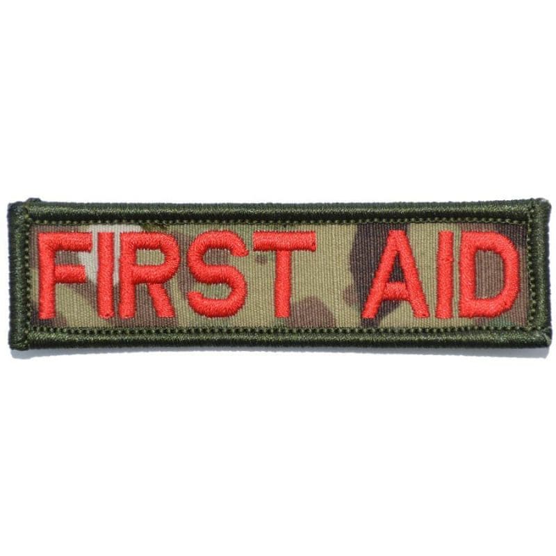 A rectangular first aid patch with red text on a camouflage pattern background.