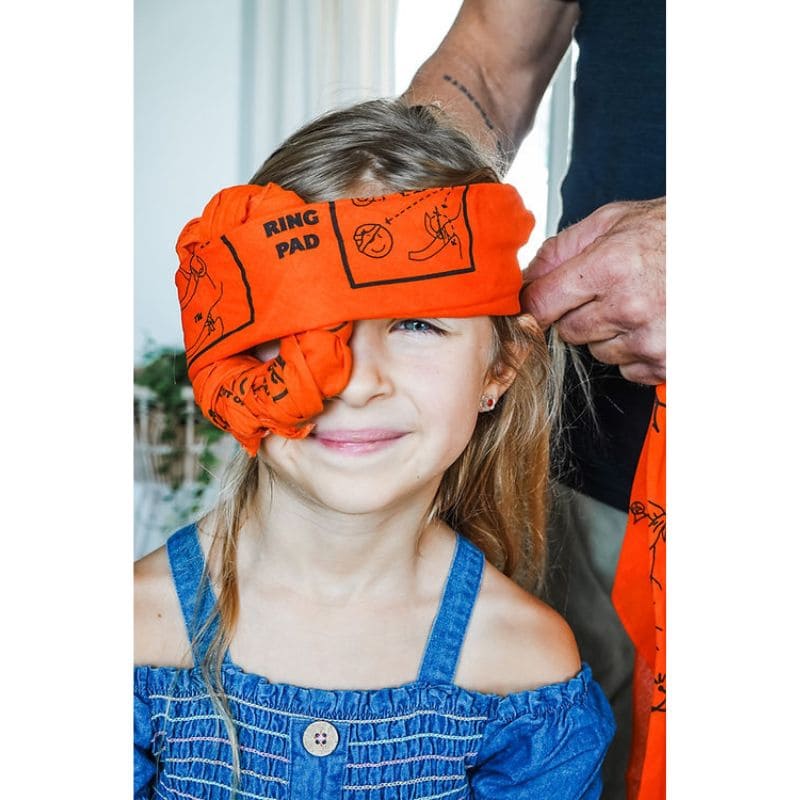 Child wearing an orange 'RING PAD' headband with a person adjusting it.