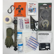 Collection of outdoor survival items including a medic multi-tool, compass, and emergency blanket on a white background.