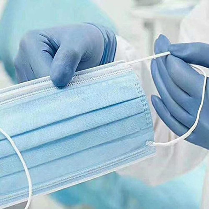 Person wearing blue gloves holding a blue surgical mask.